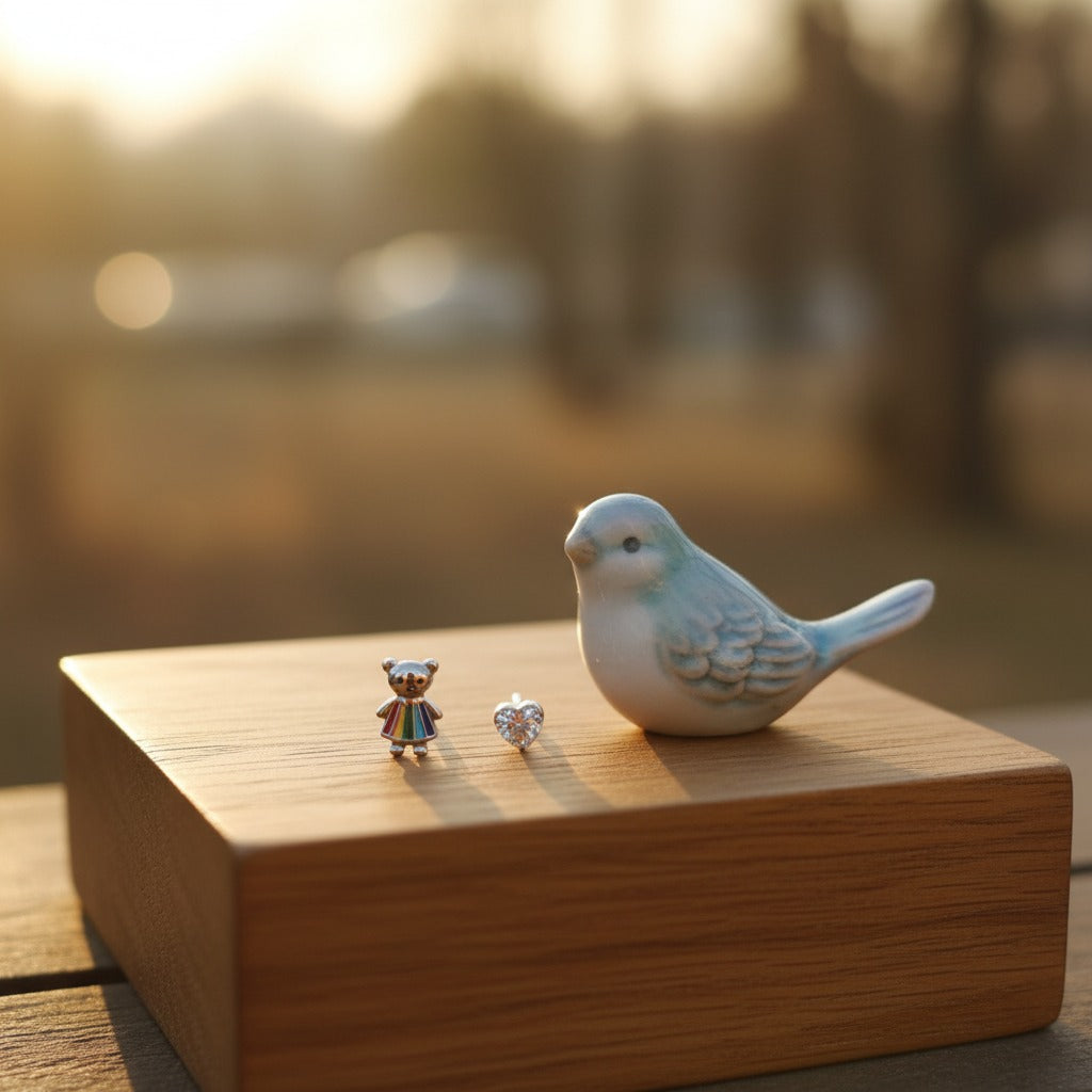 Two small earrings on a wooden surface with a ceramic bird figurine.